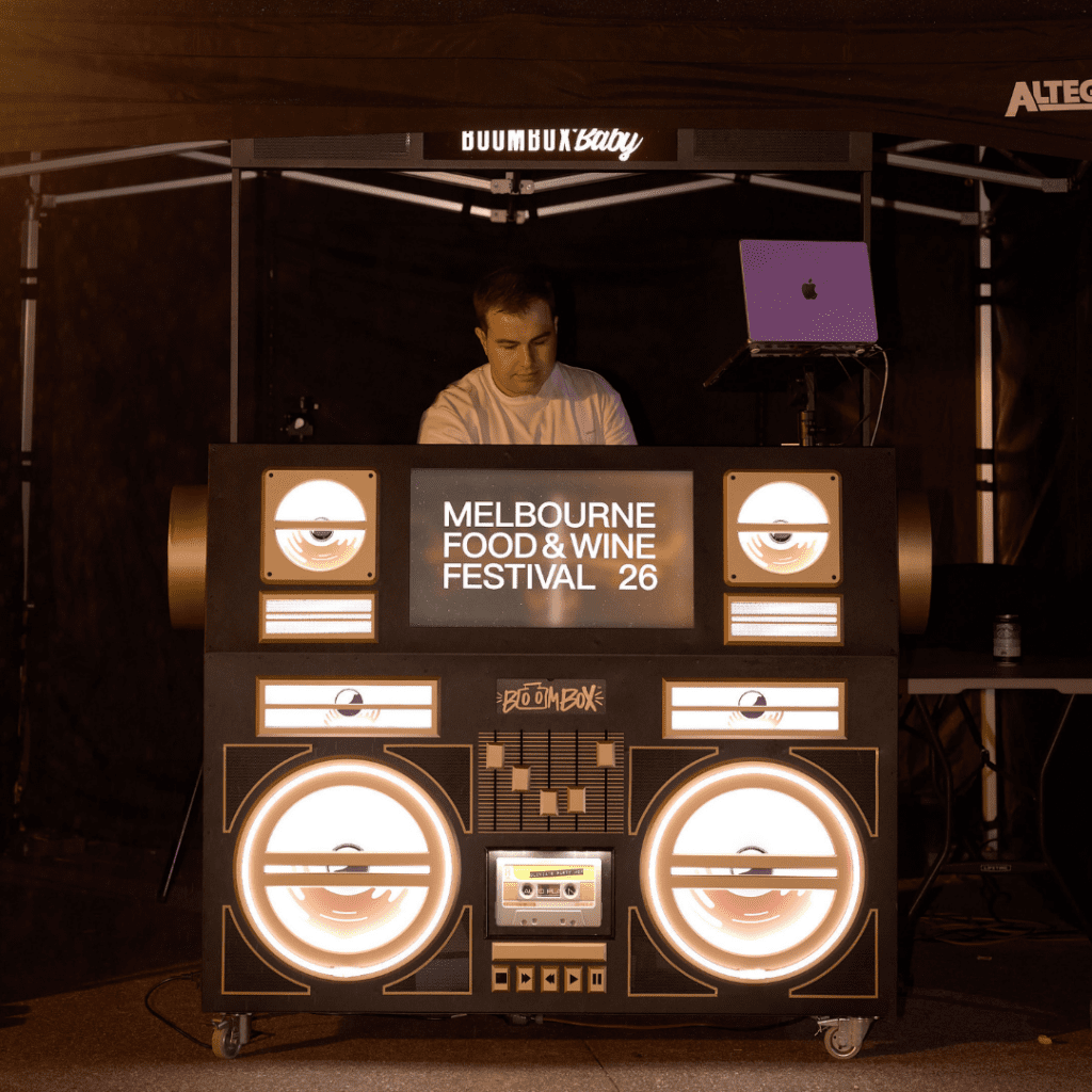 DJ performing behind an illuminated boombox-style booth branded Melbourne Food & Wine Festival 26 at An After Dark Culinary Adventure at Melbourne Zoo